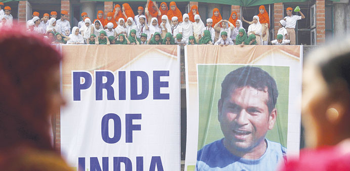 Indian students stand next to a huge poster of Sachin Tendulkar in Ahmedabad to convey their best wishes on the eve of his last Test match to be playe