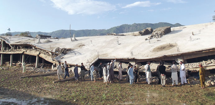 Pakistani residents gather beside a collapsed building following an earthquake in the Koga area in Buner district yesterday.