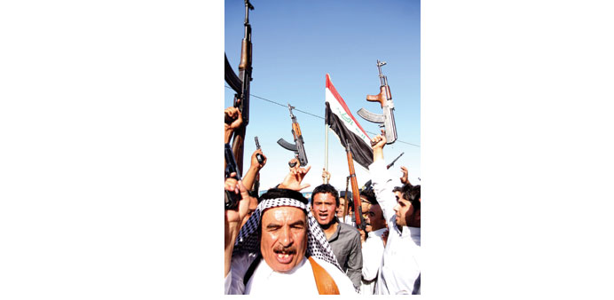 Men who have volunteered to fight with Iraqi forces carry their weapons and chant slogans in Karbala yesterday.