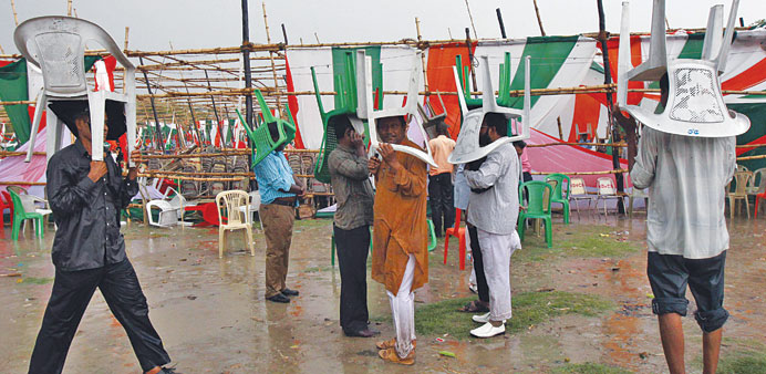 Congress Party workers use chairs to protect themselves from rain during a thunderstorm before the start of a party meeting being addressed by Rahul G