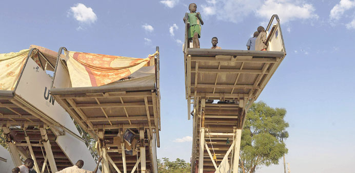 This picture taken on December 22 shows South Sudanese men sheltering under disused mobile staircases as young children play on top at a makeshift IDP