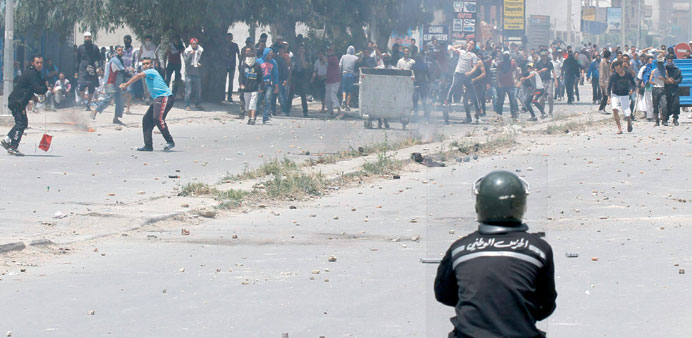 Supporters of Ansar al-Shariah throw rocks at a riot police officer during the clashes at Ettadhamen yesterday.