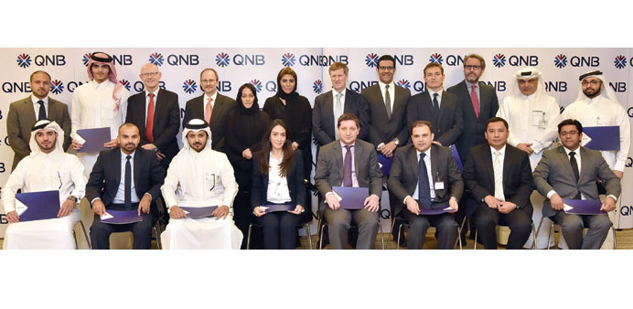 The QNB employees who graduated from the programmes are seen with officials.