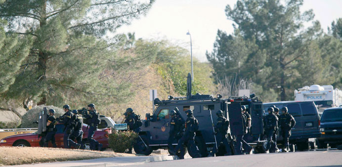 Members of a SWAT team prepare to enter the home of a suspected gunman who fired shots inside an office building during business hours in Phoenix, Ari