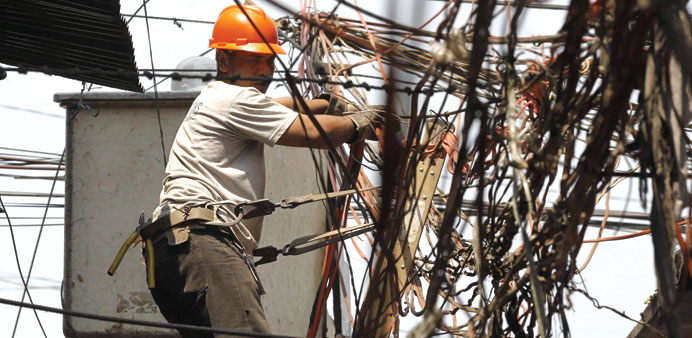 A Manila Electric Company (Meralco) worker installs a cable line at a slum in Manila yesterday.