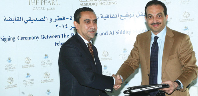 Ehab Kamel and Aly Delawar exchange documents at the agreement signing between Pearl-Qatar and Al Siddiqi Holding to open eight u201cworld-renownedu201d resta