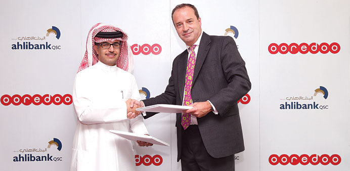 Ahmed Ali al-Mohannadi and Andrew McKechnie exchange documents after signing an agreement to launch Ahli Bank as Ooredoou2019s newest Nojoom partner.