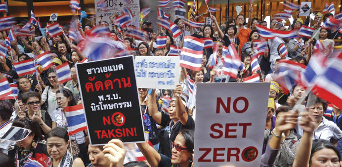    People wave flags and hold placards as thousands protest against the amnesty bill in Bangkoku2019s central business district yesterday.