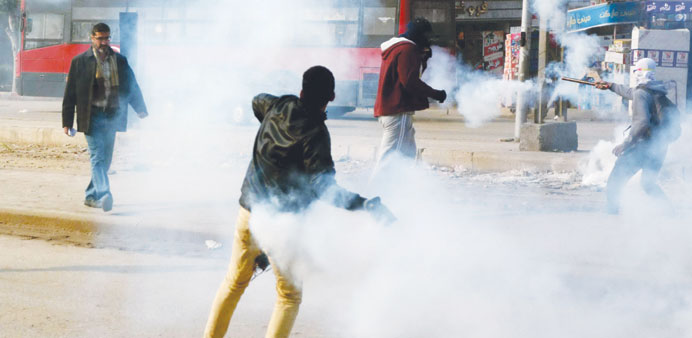 A supporter of the Muslim Brotherhood throws back a teargas shell fired by riot police during a protest in Cairo yesterday