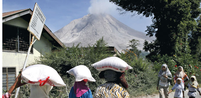 Residents carry sacks of rice after receiving food donation near the slope of Mount Sinabung volcano at Kuta Tengah village in Karo Regency, North Sum
