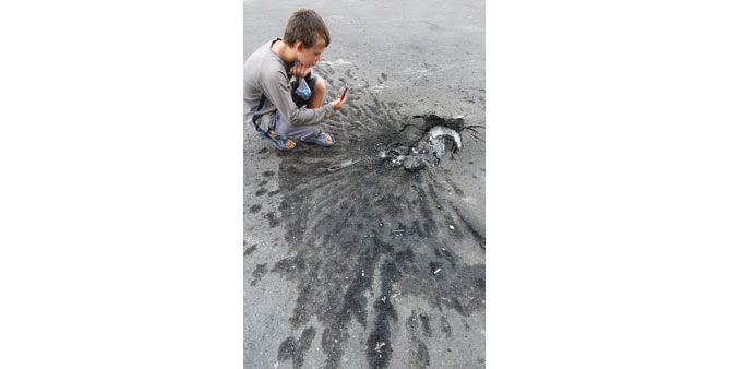 A boy takes a picture of the damage to the pavement following a mortar attack yesterday in Donetsk.