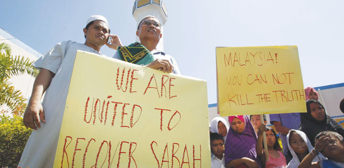 Followers of former Sultan of Sulu Jamalul Kiram III display placards while holding a brief protest in front of the Blue Mosque in Maharlika village, 