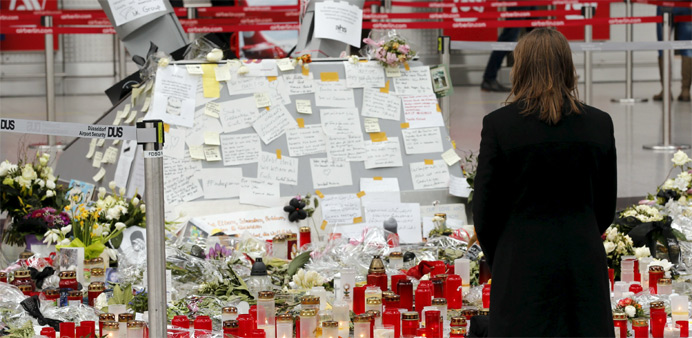 A woman kneels in front of candles and flowers as she prays for the victims of Germanwings Flight 4U
