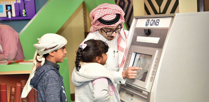  Children in front of the model of an ATM at the QNB booth (supplied picture).