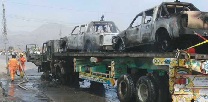 Pakistani firefighters are pictured beside a torched trailer truck transporting Nato vehicles following an attack by gunmen in the Wazir Dhand area of
