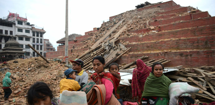 Nepalese residents walk beside buildings severely damaged by an earthquake
