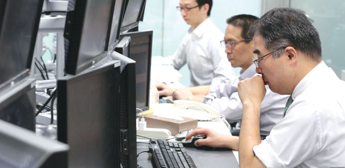 Dealers work at a foreign exchange brokerage in Tokyo. The Nikkei dropped 92.53 points to 14,914.53 points yesterday.