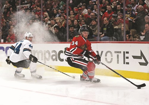 Jiri Sekac (R) of the Chicago Blackhawks turns to pass under pressure from Marc-Edouard Vlasic of the San Jose Sharks at the United Center in Chicago on Tuesday.