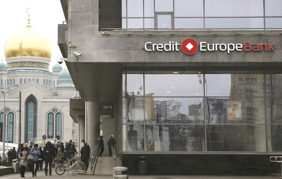 People walk near a branch of the Credit Europe Bank, with a mosque seen in the background, in Moscow, Russia yesterday. One of the sources said Fiba Groupu2019s decision to sell Credit Europe Bank was prompted by fears among the unitu2019s senior executives that their Russian entry visas might not be renewed because of the diplomatic dispute.