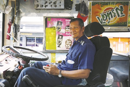 Plang Pansaior, a 66-year-old bus driver, waits for passengers while working in downtown Bangkok, Thailand.