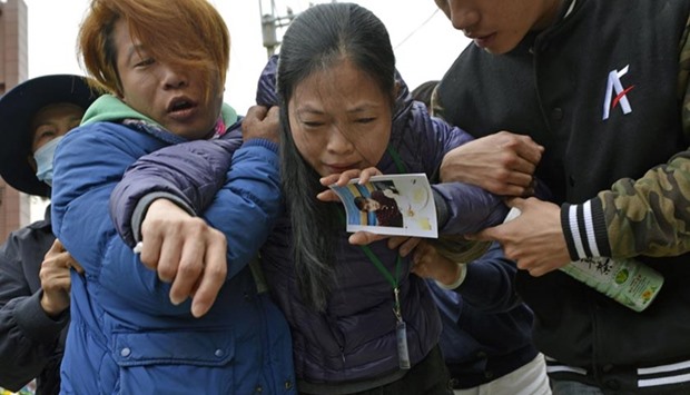 A mother holds a picture of her son after a body of a male student was recovered from the Wei-kuan complex which collapsed in the 6.4 magnitude earthquake, in Tainan, on Wednesday.