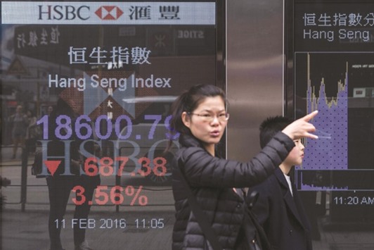 A woman gestures as she walks past a display showing the Hang Sang index outside a bank on the first day of trading of the Lunar New Year in Hong Kong. The index slumped almost 4% to their lowest levels since June 2012 yesterday.