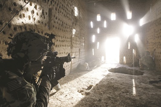 US soldier Nicholas Dickhut from 5-20 infantry Regiment attached to 82nd Airborne points his rifle at a doorway after coming under fire by the Taliban while on patrol in Zharay district in Kandahar province, southern Afghanistan in this April 26, 2012 file photo. Pressure is growing on the US military to do more to help Afghan forces repel the threat posed by Taliban militants.