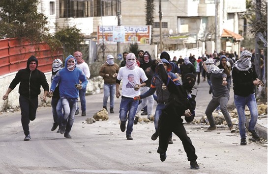 Palestinians throw stones at Israeli forces during clashes yesterday in the Arroub refugee camp, north of the West Bank city of Hebron. Clashes erupted following the funeral of a Palestinian youth who the Israel army said was shot and killed by Israeli troops after throwing stones on Wednesday at Israeli vehicles on a road in the occupied West Bank.