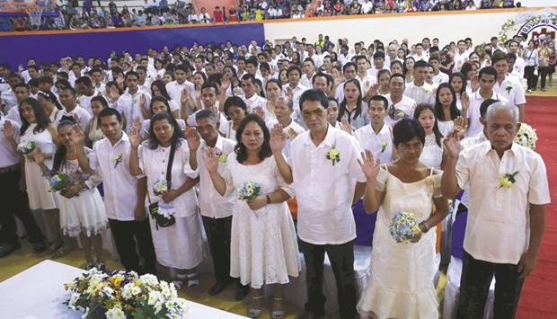Filipino couples raise their hands in oath during a mass wedding ceremony ahead of Valentineu2019s Day celebration in Manila yesterday. More than 350 couples tied the knot in a mass wedding sponsored by the local government of Manila.