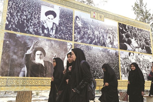 Schoolgirls walk past a giant board displaying pictures of Ayatollah Khomeini as Iranians mark the start of 10 days of celebrations for the 37th anniversary of the Islamic revolution yesterday at the Behesht-e Zahra cemetery in southern Tehran.