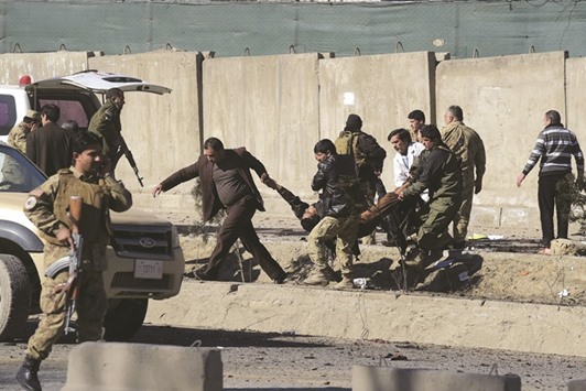 Afghan security personnels carry a victim at the site of a suicide car bomb next to a police base in Kabul yesterday.
