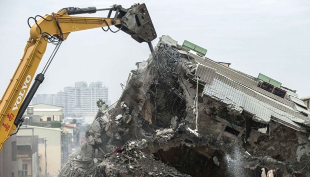 An excavator breaks open the remains of apartments during the search and rescue operation at the Wei-Kuan complex.