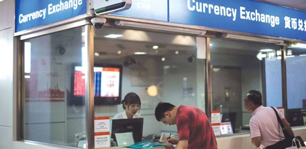 A man changes foreign currency into Chinese yuan at a currency exchange office in Hongqiao airport in Shanghai. The yuan may trade between 6.6 per dollar and about 7 per dollar by year-end, according to Goldman Sachs.