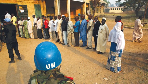 A UN security officer keeps guard as people wait to cast their votes in the second round of presidential and legislative elections in the PK5 neighbourhood of Bangui.