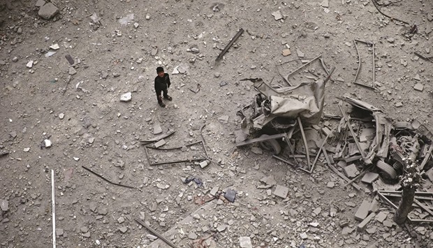 A boy looking up as he inspects the damage after airstrikes by pro-Syrian government forces in the rebel held Douma neighbourhood of Damascus yesterday.