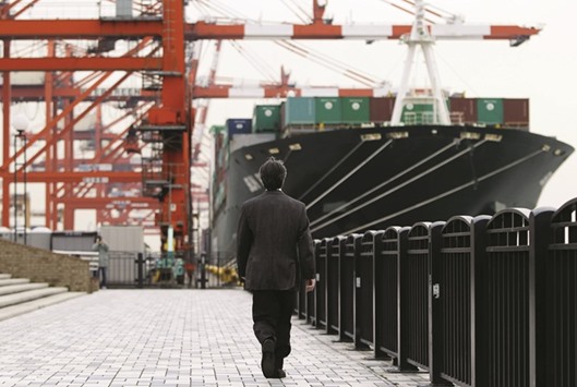 A man walks near a container ship at a port in Tokyo. Japanu2019s economy shrank more than expected in the final quarter of last year as consumer spending and exports slumped, adding to headaches for policymakers already wary of damage the financial market rout could inflict on a fragile recovery.
