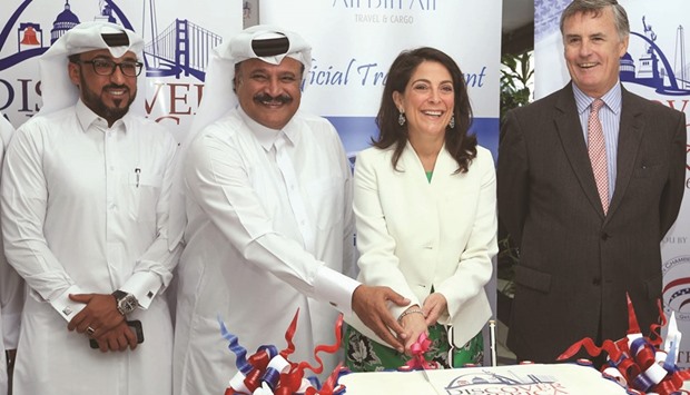 Ambassador Dana Shell Smith and Saeed al-Hajri cut a cake at the main office of Ali Bin Ali Travel in Doha as other dignitaries look on.