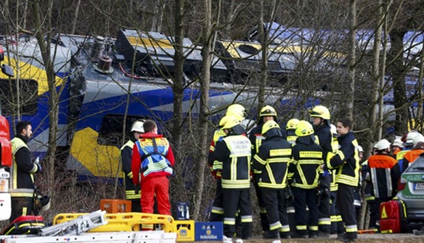 Members of emergency services stand next to a crashed train near Bad Aibling