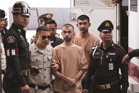 Suspects of last yearu2019s Bangkok blast Bilal Mohamed (centre) and Yusufu Mieraili are escorted by prison officers as they arrive at the military court in Bangkok yesterday.