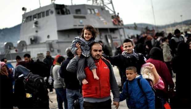 Refugees and migrants disembark from a Greek coast guard vessel in Mytilene