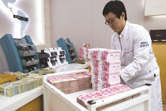 An employee arranges yuan banknotes at the Korea Exchange Bank headquarters in Seoul. Twelve-month forwards for the offshore yuan rallied 2% so far this month in Hong Kong, outperforming the exchange rateu2019s 1.2% gain, data compiled by Bloomberg show.