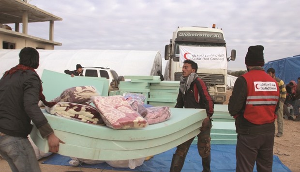 QRCS personnel transporting mattresses for displaced Syrian families.