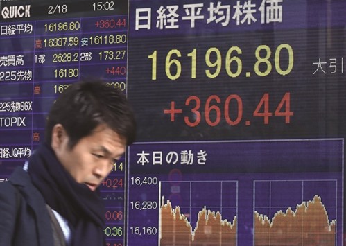 A pedestrian walks past a share prices board in Tokyo. Japanese shares ended trading 2.3% higher yesterday.