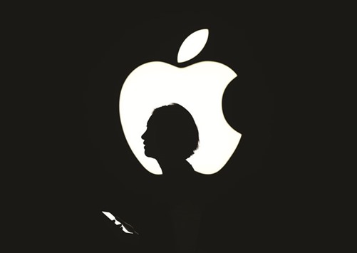 The file photo taken on September 9, 2015 shows a reporter walking by an Apple logo during a media event in San Francisco, California. From Google to Facebook, the industryu2019s biggest names have rallied around Appleu2019s CEO after he vowed to resist a court order demanding it help unlock the iPhone of a shooter in a terrorist attack.