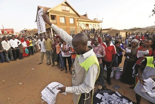 Electoral officials count votes at a polling station in Kampala as voting closes.