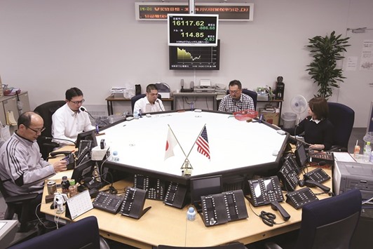 Currency traders work in the dealing room of a foreign exchange brokerage in Tokyo. Nomura Holdings is sticking to its forecast for the yen to weaken to 130 per dollar by year-end.