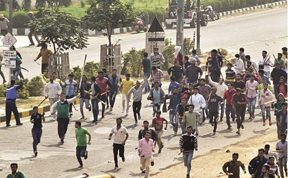 Protesters run along a street during violence after rival caste groups clashed during a mass rally over access to jobs and education in Rohtak, Harayana, yesterday.