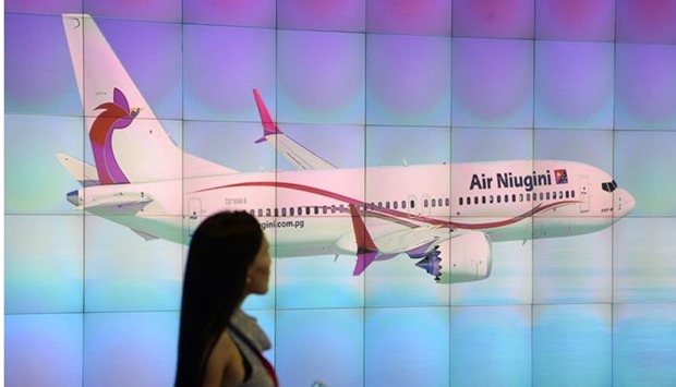 A visitor walks past a screen displaying a passenger plane from Papua New Guinea airline Air Niugini, at the Singapore Airshow in Singapore on Friday.