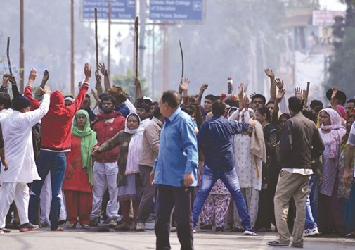 Residents gather on a street as others gesture to hold them back amid ongoing caste protests in Rohtak yesterday.