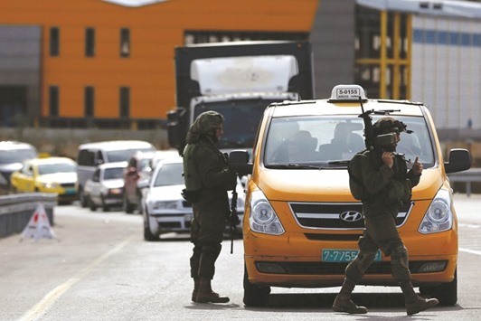 An Israeli soldier checks the documents of the Palestinian passengers of a taxi on their way out of the West Bank village of Ein Sinya, northern Ramallah, yesterday.